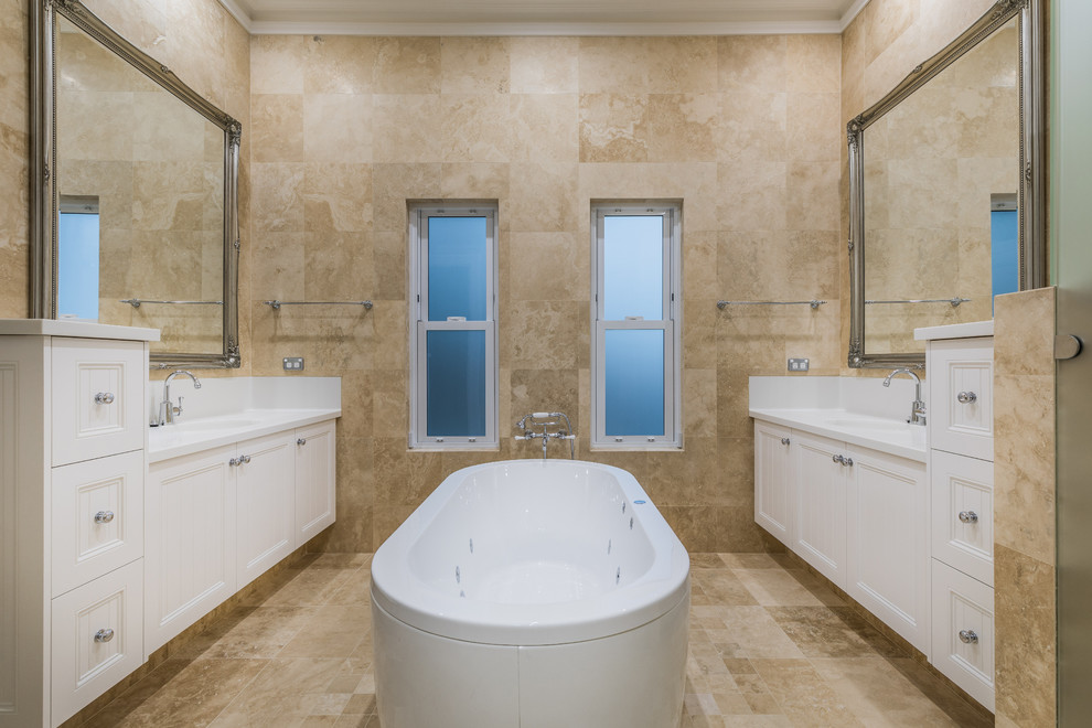 Design ideas for a traditional master bathroom in Perth with recessed-panel cabinets, white cabinets, a freestanding tub, beige tile, beige walls, an undermount sink, beige floor and white benchtops.