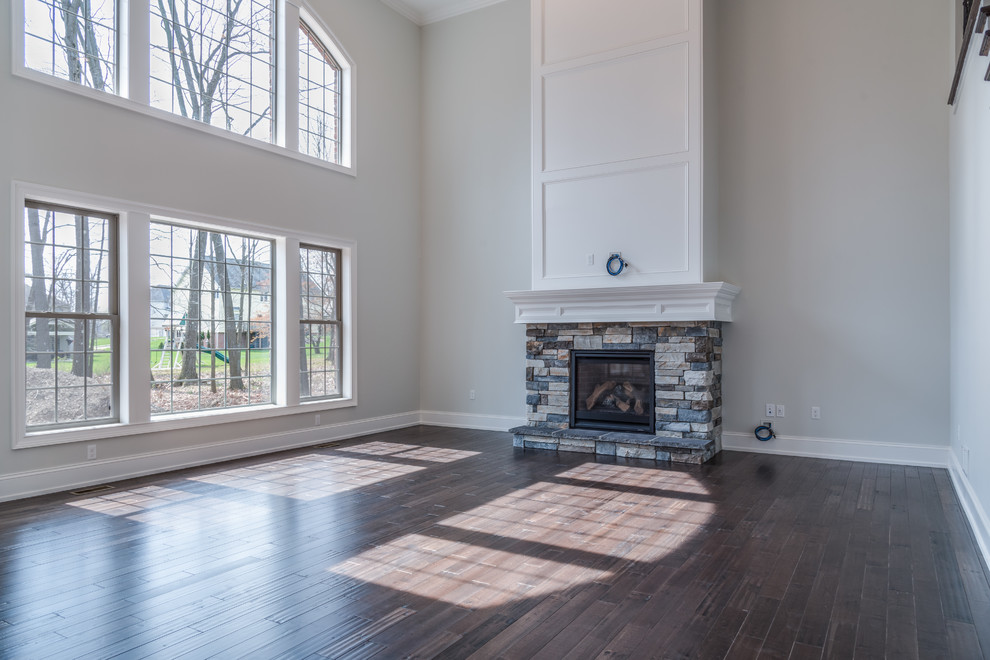 Large transitional open concept dark wood floor and brown floor home design photo with gray walls, a standard fireplace, a stone fireplace and a wall-mounted tv