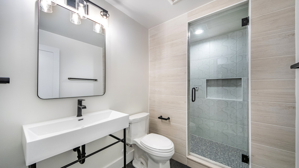 Mid-sized transitional master beige tile and porcelain tile ceramic tile, brown floor and single-sink alcove shower photo in DC Metro with open cabinets, black cabinets, a two-piece toilet, white walls, a pedestal sink, quartz countertops, a hinged shower door, white countertops, a niche and a freestanding vanity