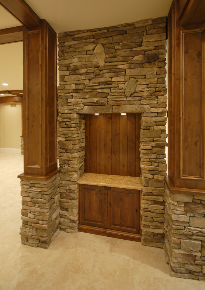 Basement - large rustic carpeted and beige floor basement idea in Birmingham with beige walls, a two-sided fireplace and a stone fireplace