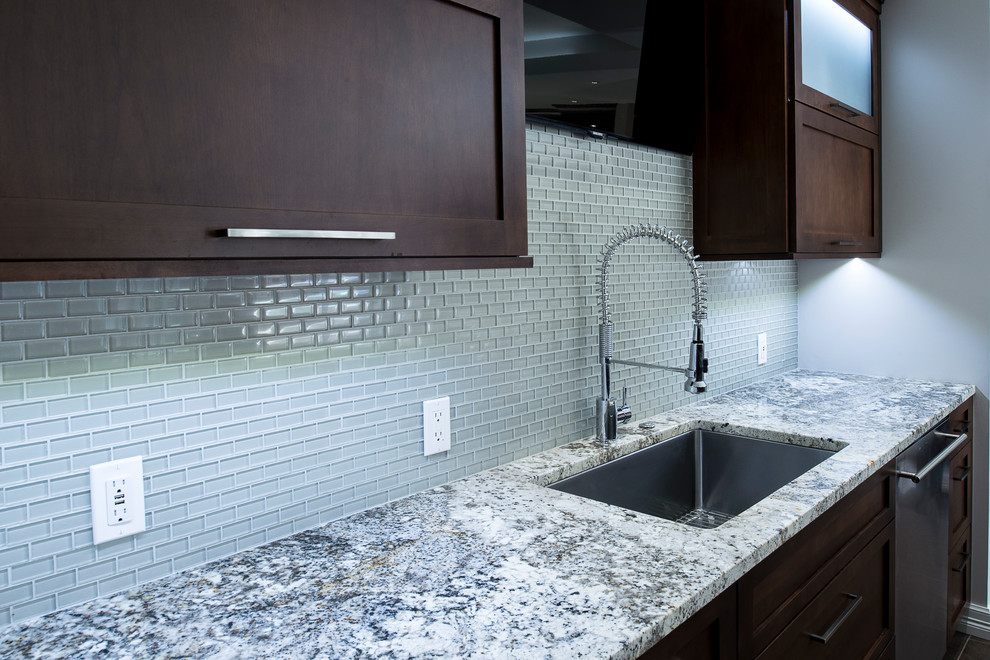 Large transitional ceramic tile and beige floor eat-in kitchen photo with an undermount sink, shaker cabinets, brown cabinets, granite countertops, stainless steel appliances, an island, white backsplash and glass tile backsplash