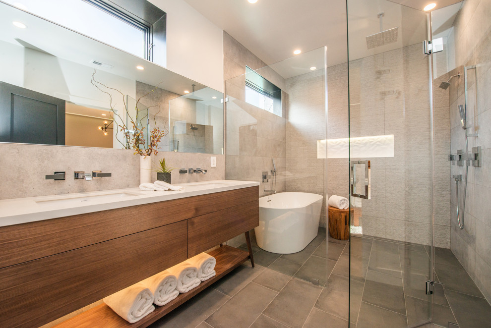 Example of a trendy master gray tile gray floor and double-sink bathroom design in Los Angeles with flat-panel cabinets, medium tone wood cabinets, white walls, an undermount sink, a hinged shower door, white countertops, a niche and a freestanding vanity