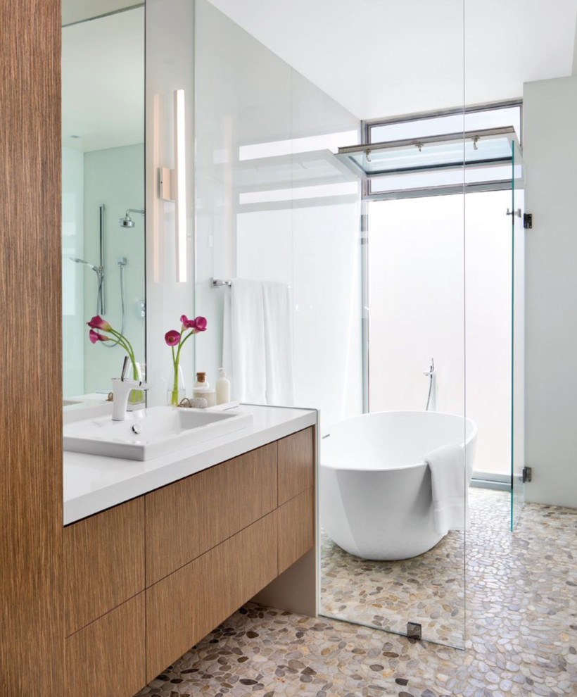 This is an example of a large contemporary master bathroom in San Diego with flat-panel cabinets, medium wood cabinets, a freestanding tub, white walls, pebble tile floors, a drop-in sink, a curbless shower and an open shower.