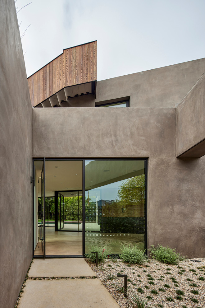 Cette image montre un très grand vestibule minimaliste en bois avec un mur beige, sol en béton ciré, une porte pivot, une porte noire et un sol gris.