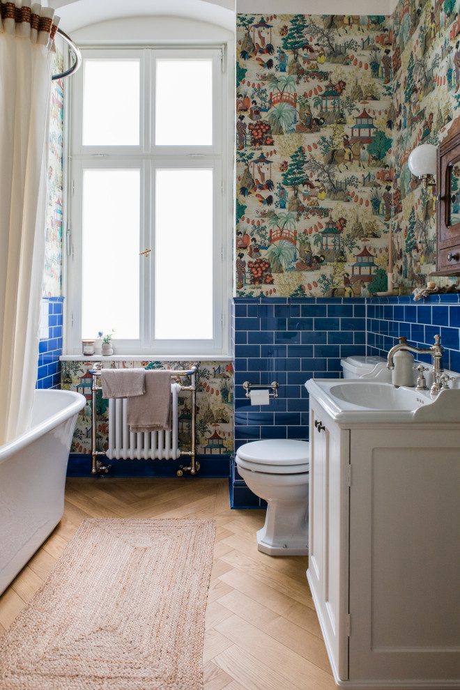 Imagen de cuarto de baño bohemio pequeño con bañera exenta, suelo de madera en tonos medios y papel pintado