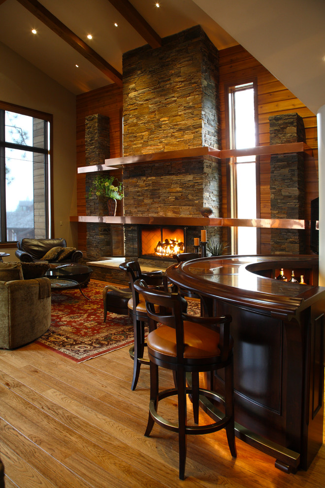 This is an example of a large arts and crafts formal open concept living room in Seattle with brown walls, medium hardwood floors, a standard fireplace, a stone fireplace surround and a wall-mounted tv.