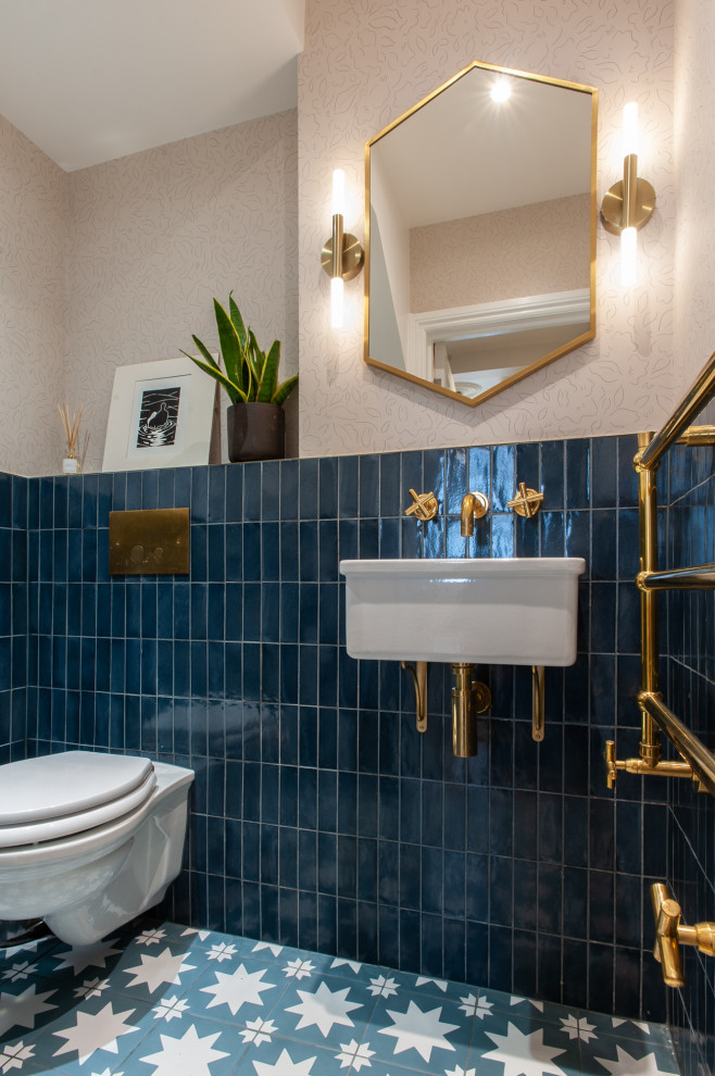 Design ideas for a large classic cloakroom in London with a wall mounted toilet, blue tiles, ceramic tiles, porcelain flooring, a wall-mounted sink, blue floors, wallpapered walls and pink walls.