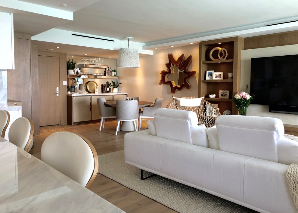 This is an example of a mid-sized modern open concept family room in Miami with a home bar, white walls, light hardwood floors, no fireplace, a built-in media wall and beige floor.