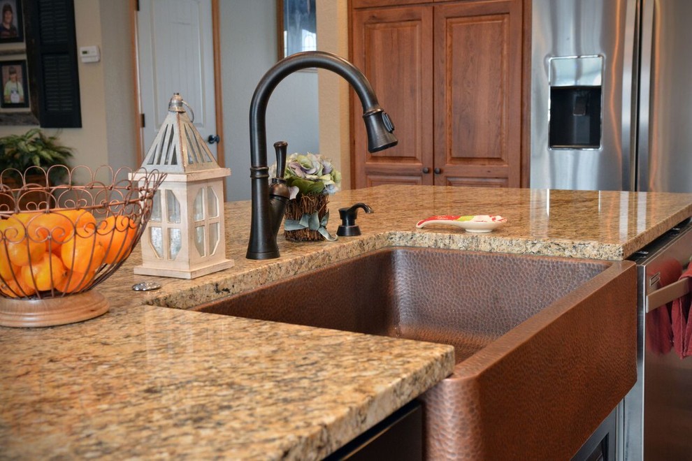 Inspiration for a large transitional l-shaped medium tone wood floor kitchen remodel with a farmhouse sink, raised-panel cabinets, light wood cabinets, granite countertops, stainless steel appliances and an island