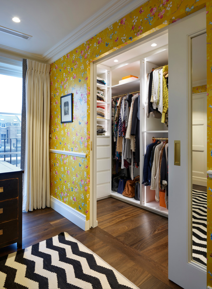 Inspiration for a mid-sized traditional gender-neutral walk-in wardrobe in London with open cabinets, white cabinets, medium hardwood floors and brown floor.