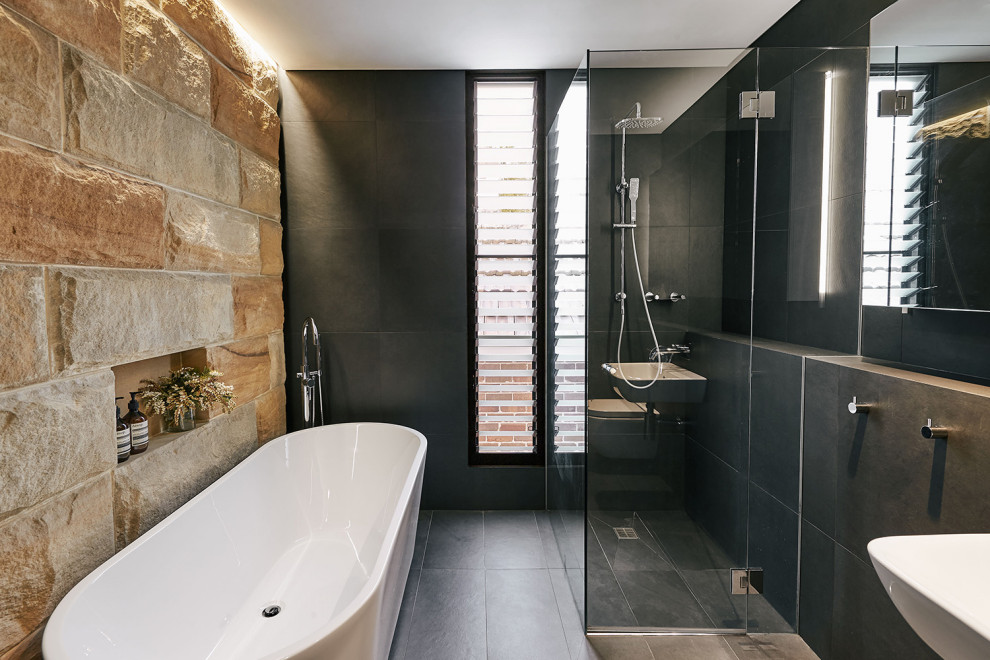 Design ideas for a mid-sized contemporary master bathroom in Sydney with a freestanding tub, a corner shower, a wall-mount toilet, gray tile, a wall-mount sink, grey floor and a shower curtain.