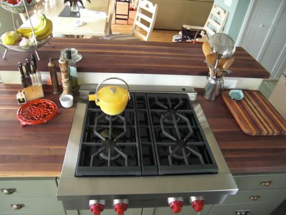 Mid-sized transitional l-shaped porcelain tile and gray floor open concept kitchen photo in Seattle with a farmhouse sink, shaker cabinets, green cabinets, wood countertops, white backsplash, ceramic backsplash, stainless steel appliances and an island