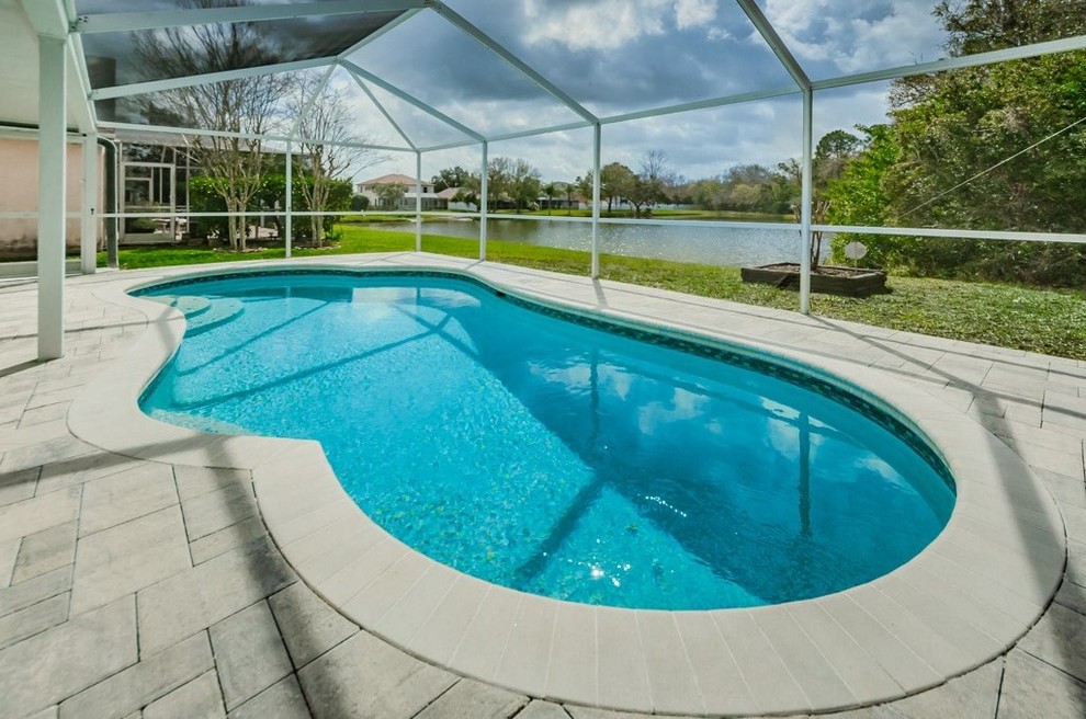 Mid-sized beach style backyard kidney-shaped natural pool in Tampa with decking.