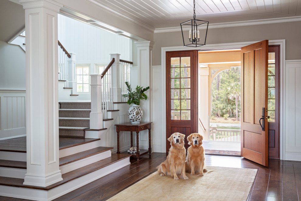 This is an example of a beach style foyer in Charleston with grey walls, dark hardwood floors, a single front door, a medium wood front door, brown floor, timber and decorative wall panelling.