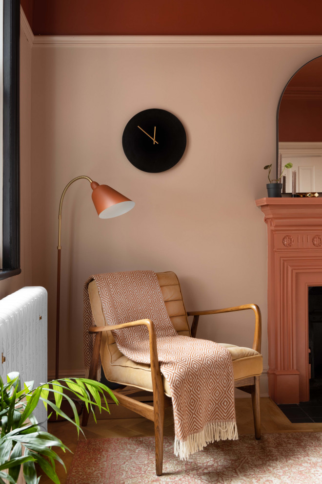 Ispirazione per una piccola sala da pranzo aperta verso la cucina minimalista con pareti rosa, parquet chiaro, camino classico e cornice del camino in metallo