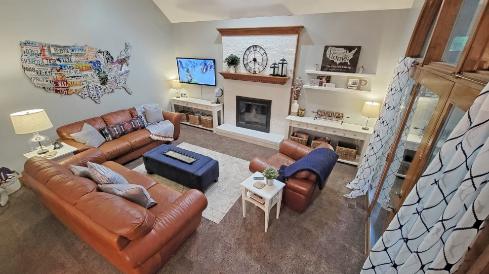 Photo of a small open plan games room with grey walls, carpet, a standard fireplace, a brick fireplace surround, a wall mounted tv and a vaulted ceiling.