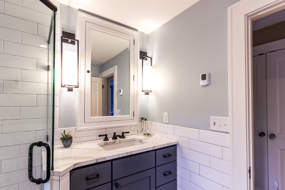 Large transitional master bathroom in Minneapolis with flat-panel cabinets, blue cabinets, a corner shower, a one-piece toilet, white tile, subway tile, grey walls, an undermount sink, engineered quartz benchtops, a hinged shower door and beige benchtops.