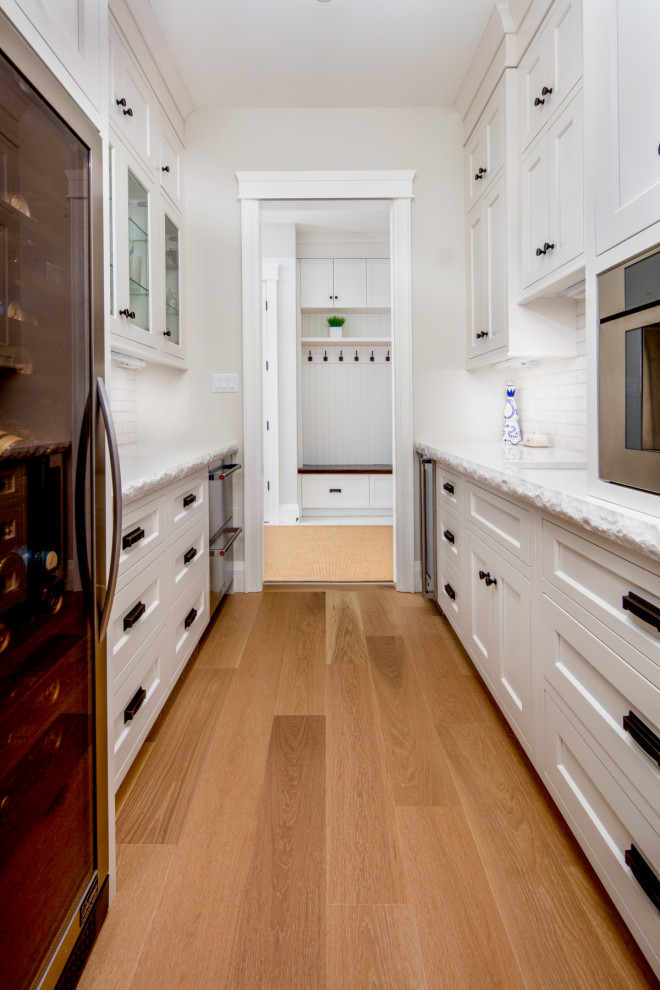 Eat-in kitchen - large rustic l-shaped light wood floor and beige floor eat-in kitchen idea in Toronto with a farmhouse sink, shaker cabinets, white cabinets, quartz countertops, white backsplash, subway tile backsplash, paneled appliances, an island and white countertops