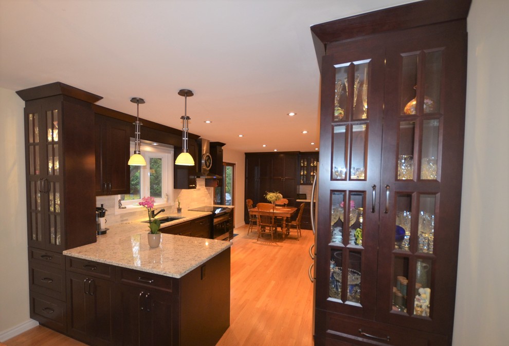 Mid-sized transitional galley medium tone wood floor and brown floor eat-in kitchen photo in Ottawa with recessed-panel cabinets, dark wood cabinets, granite countertops, gray backsplash, stainless steel appliances, a double-bowl sink, porcelain backsplash, a peninsula and beige countertops