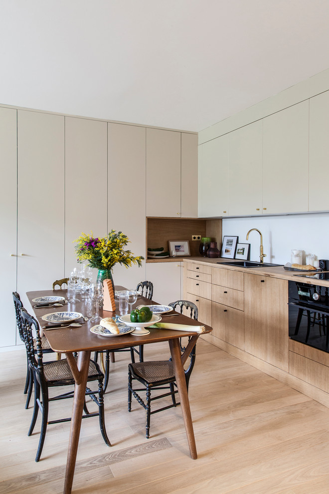 Inspiration for a contemporary l-shaped eat-in kitchen in Paris with a drop-in sink, flat-panel cabinets, medium wood cabinets, wood benchtops, light hardwood floors, no island, beige floor and brown benchtop.
