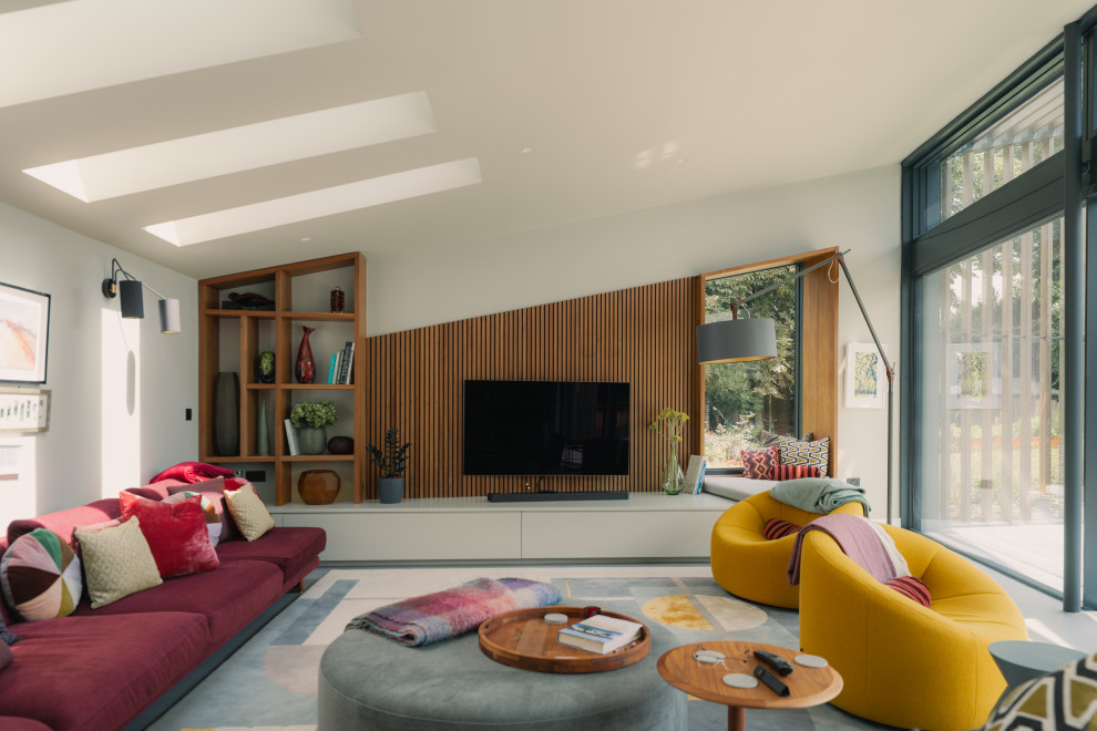 This is an example of a large contemporary open plan living room in Cambridgeshire with a wall mounted tv, a vaulted ceiling, multi-coloured walls, white floors and feature lighting.
