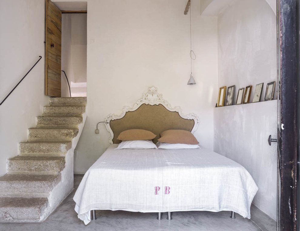 This is an example of a mid-sized mediterranean guest bedroom in Marseille with white walls, concrete floors and no fireplace.