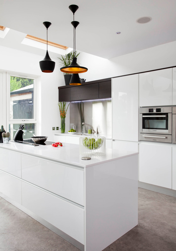 Exempel på ett stort modernt linjärt kök och matrum, med en undermonterad diskho, släta luckor, vita skåp, bänkskiva i kvartsit, grått stänkskydd, rostfria vitvaror, betonggolv, en köksö och grått golv