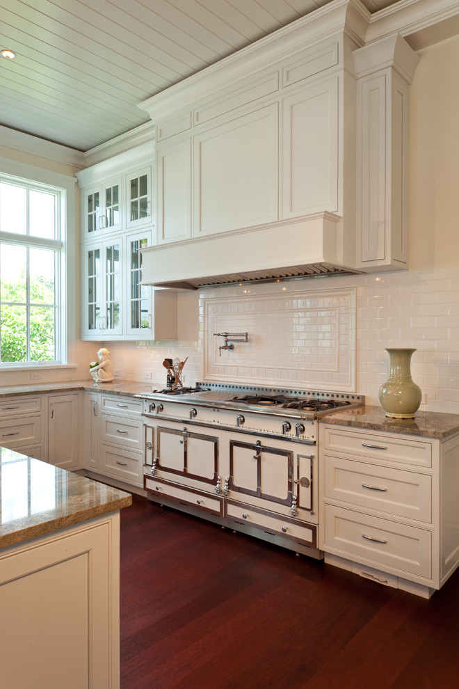 Design ideas for a mid-sized traditional l-shaped eat-in kitchen in Tampa with subway tile splashback, white appliances, shaker cabinets, white cabinets, granite benchtops, white splashback, dark hardwood floors, with island, brown floor and a double-bowl sink.