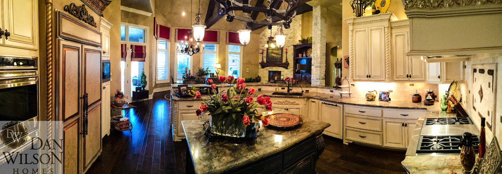 Inspiration for a large traditional u-shaped open plan kitchen in Austin with an undermount sink, raised-panel cabinets, distressed cabinets, granite benchtops, beige splashback, stone tile splashback, stainless steel appliances, dark hardwood floors and with island.