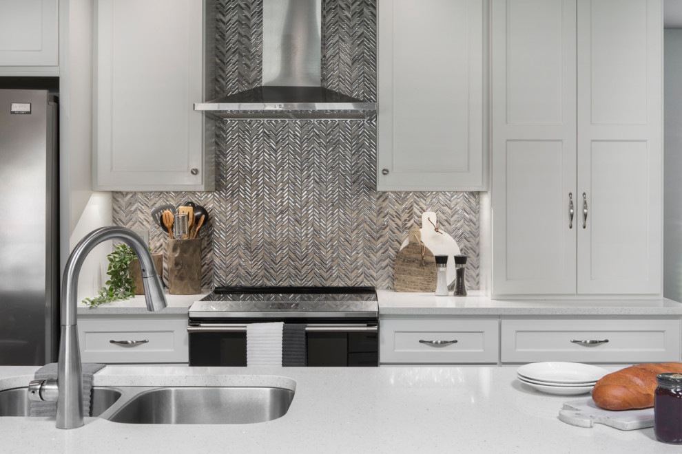 Mid-sized transitional galley brown floor eat-in kitchen photo with an undermount sink, shaker cabinets, white cabinets, quartzite countertops, beige backsplash, mosaic tile backsplash, stainless steel appliances, a peninsula and white countertops