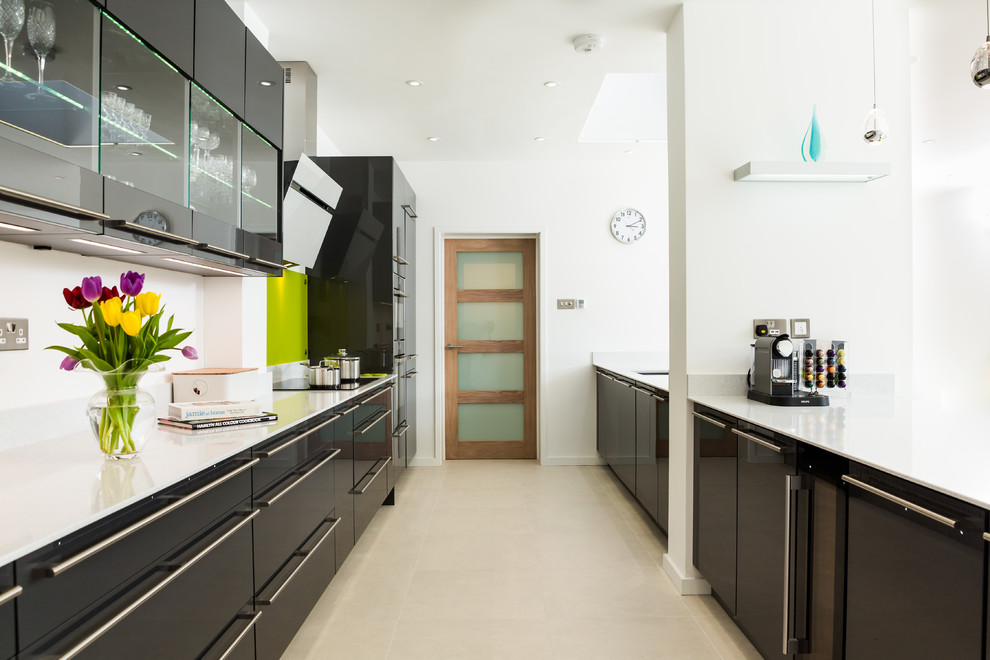 Design ideas for a large contemporary galley eat-in kitchen in Hampshire with flat-panel cabinets, green splashback, glass sheet splashback, multiple islands, an integrated sink, grey cabinets, quartzite benchtops, panelled appliances and porcelain floors.