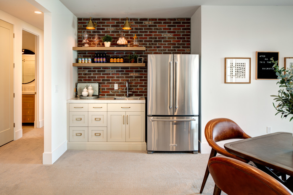 Mid-sized traditional single-wall wet bar in Salt Lake City with a drop-in sink, shaker cabinets, white cabinets, marble benchtops, red splashback, brick splashback, carpet, beige floor and multi-coloured benchtop.