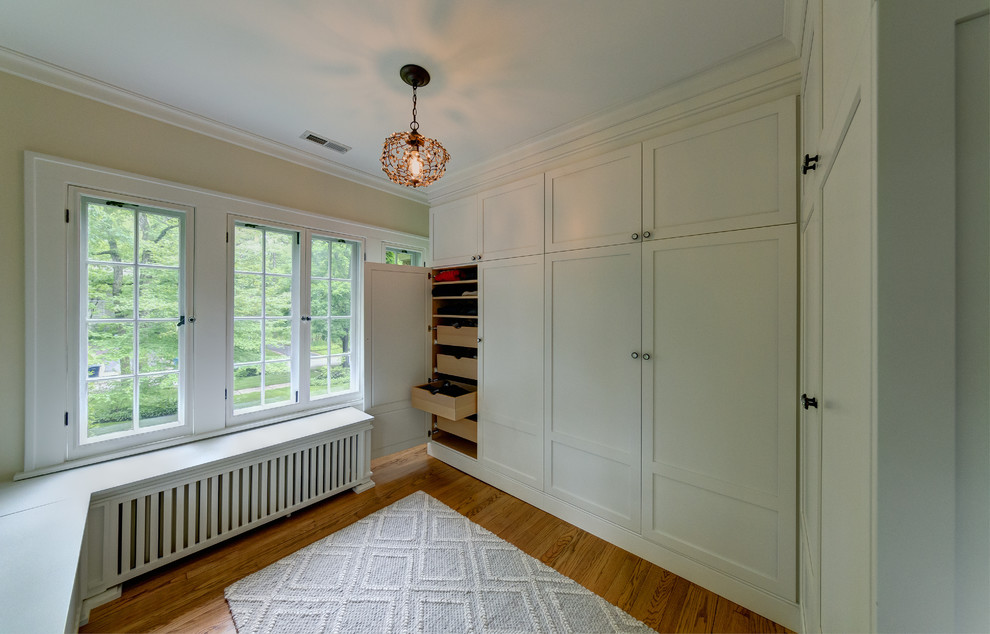 Photo of a traditional gender-neutral dressing room in Chicago with shaker cabinets, white cabinets and medium hardwood floors.
