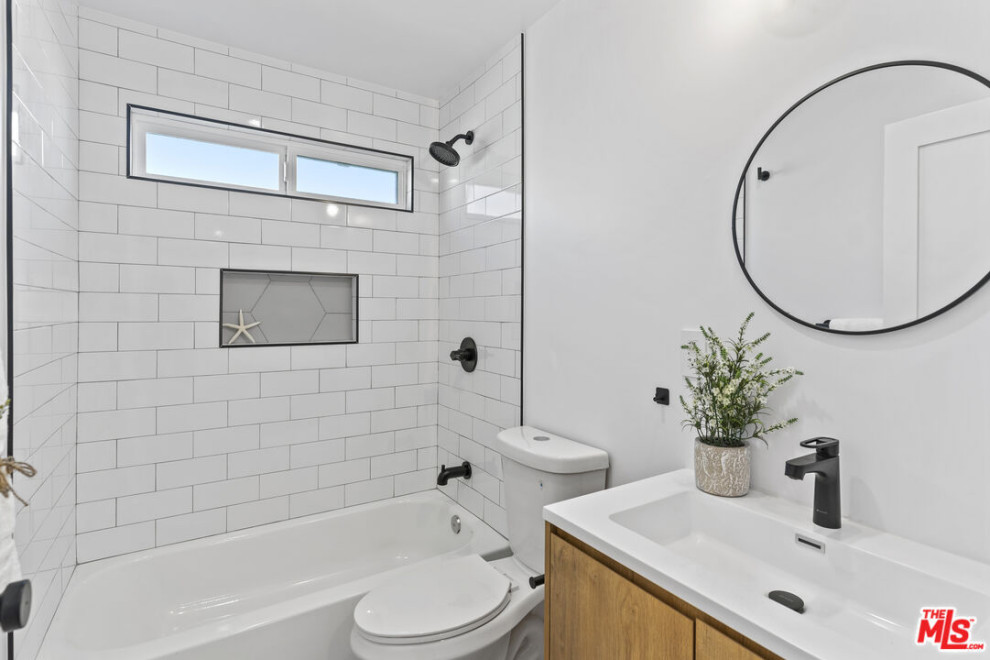 Contemporary bathroom in Los Angeles with flat-panel cabinets, brown cabinets, an alcove bath, a shower/bath combination, a one-piece toilet, white tiles, ceramic tiles, white walls, ceramic flooring, an integrated sink, engineered stone worktops, white floors, a shower curtain, white worktops, a wall niche, a single sink and a built in vanity unit.
