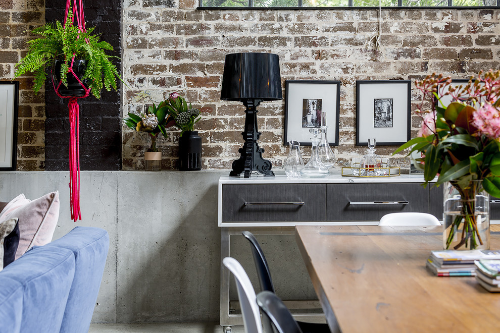 Design ideas for an expansive industrial open plan dining in Sydney with concrete floors, a wood stove, a concrete fireplace surround and grey floor.