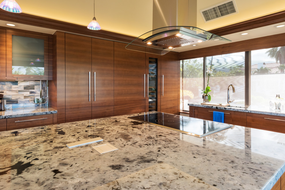Inspiration for a contemporary u-shaped kitchen in Hawaii with a single-bowl sink, flat-panel cabinets, medium wood cabinets, granite benchtops, blue splashback, glass tile splashback, panelled appliances, porcelain floors, with island, brown floor and white benchtop.
