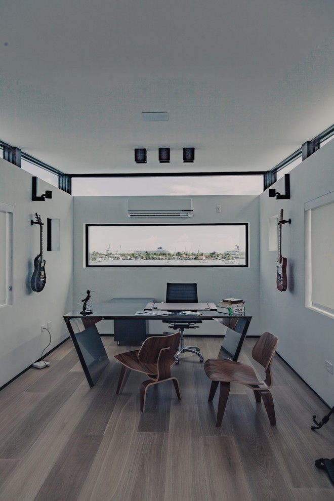 This is an example of a contemporary home office in New York with light hardwood floors.