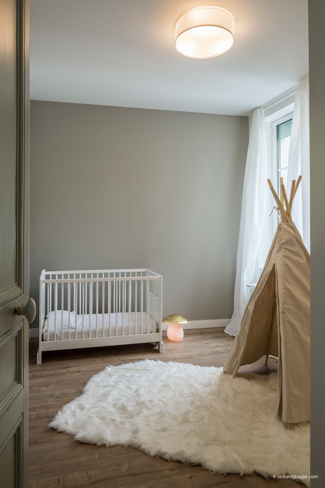 Photo of a transitional nursery for girls in Other with grey walls, dark hardwood floors and brown floor.