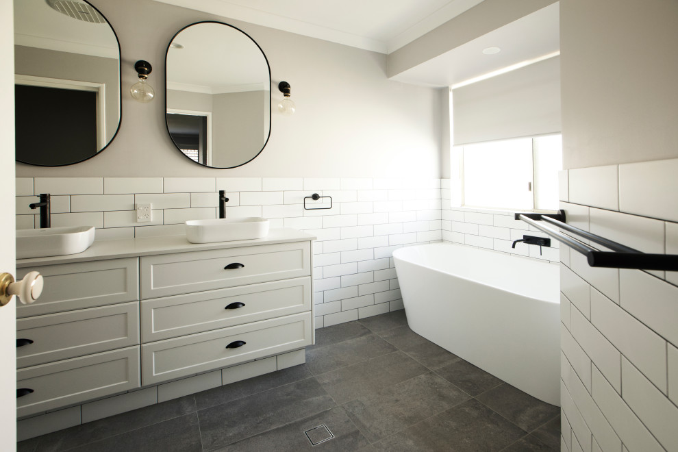 Inspiration for a mid-sized industrial master bathroom in Perth with shaker cabinets, dark wood cabinets, a freestanding tub, a corner shower, a one-piece toilet, beige tile, ceramic tile, beige walls, ceramic floors, a vessel sink and a hinged shower door.