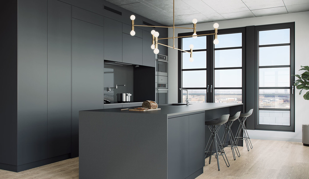 Inspiration for a large modern open plan kitchen in Montreal with an undermount sink, flat-panel cabinets, grey cabinets, laminate benchtops, black splashback, glass tile splashback, light hardwood floors and with island.