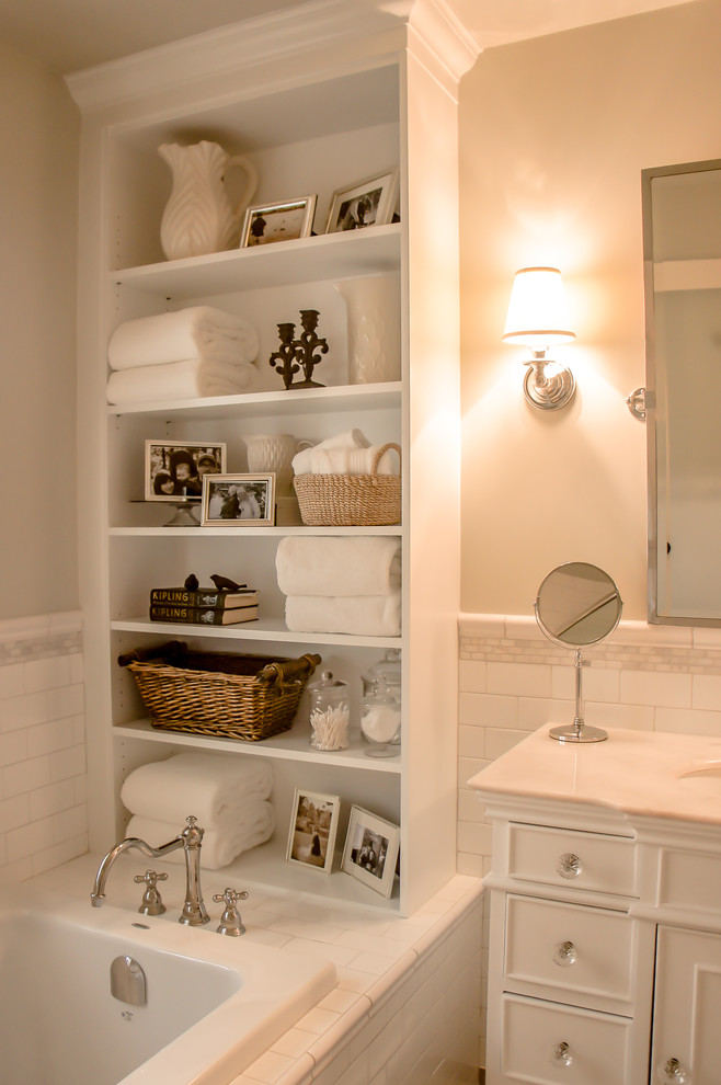 Photo of a large traditional master bathroom in Ottawa with a drop-in sink, raised-panel cabinets, white cabinets, marble benchtops, a drop-in tub, a corner shower, a one-piece toilet, white tile, subway tile, grey walls and porcelain floors.
