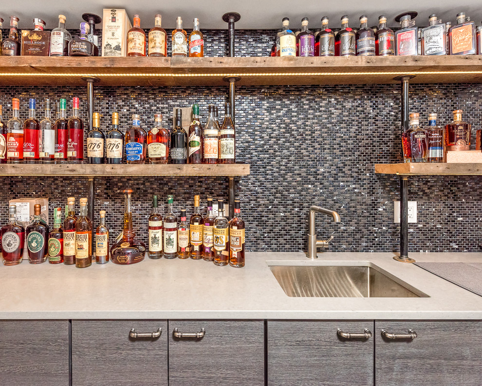 Photo of a mid-sized industrial single-wall wet bar in Chicago with an undermount sink, flat-panel cabinets, dark wood cabinets, light hardwood floors, beige floor and mosaic tile splashback.