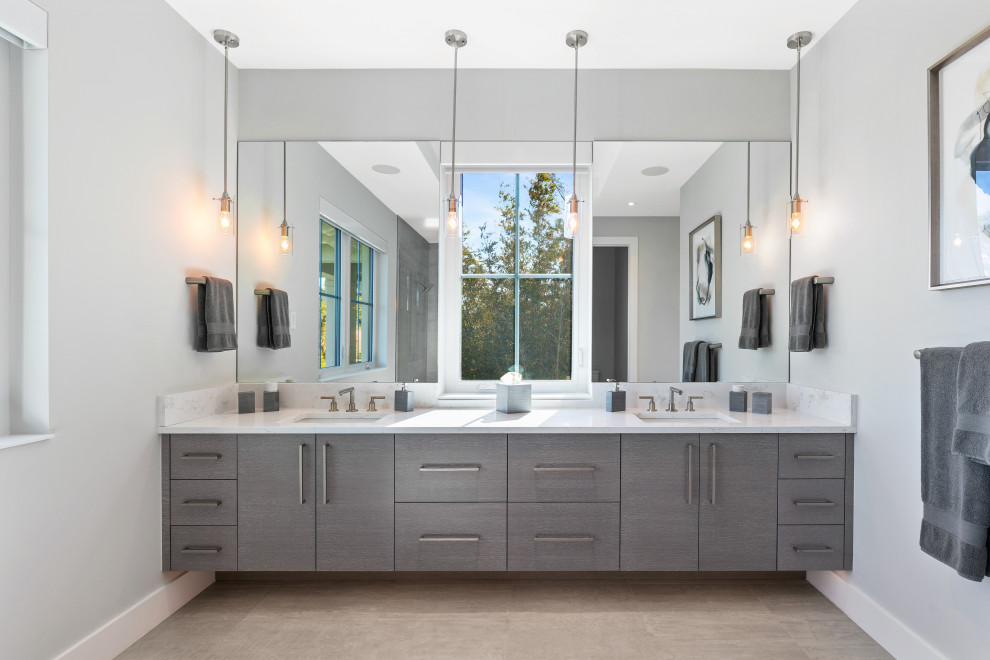 Inspiration for a mid-sized beach style master bathroom in Tampa with flat-panel cabinets, grey cabinets, a curbless shower, a two-piece toilet, gray tile, porcelain tile, grey walls, porcelain floors, an undermount sink, engineered quartz benchtops, grey floor, a hinged shower door and white benchtops.