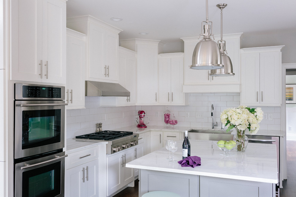 Inspiration for a large transitional u-shaped dark wood floor eat-in kitchen remodel in Atlanta with a farmhouse sink, shaker cabinets, white cabinets, marble countertops, white backsplash, ceramic backsplash, stainless steel appliances and an island