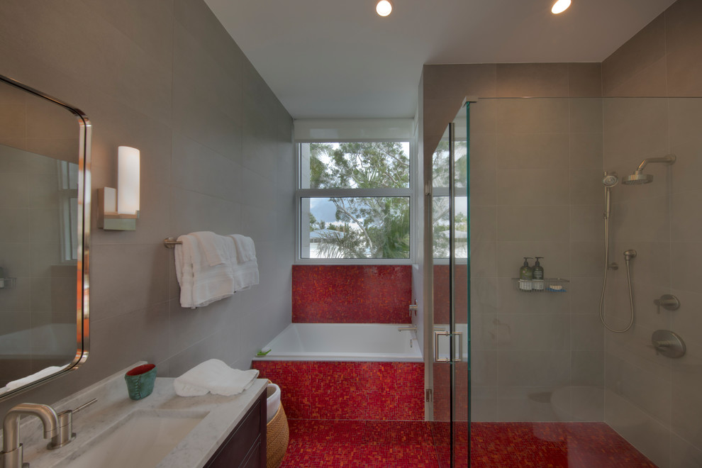 Large modern bathroom in Miami with brown cabinets, a corner shower, red tile, grey walls, light hardwood floors and red floor.