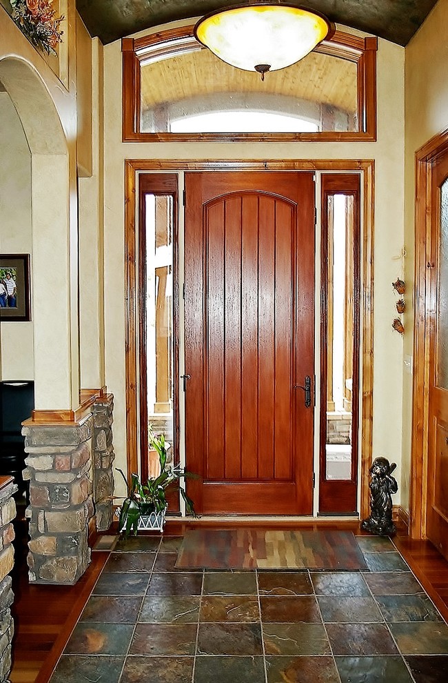 Photo of a mid-sized arts and crafts foyer in Denver with slate floors, a single front door, a medium wood front door, beige walls, multi-coloured floor and vaulted.