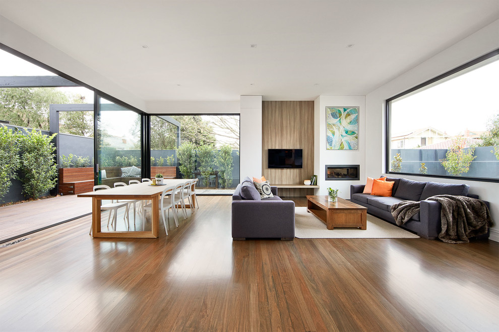 Inspiration for a contemporary formal open concept living room in Melbourne with white walls, medium hardwood floors, a ribbon fireplace and a wall-mounted tv.