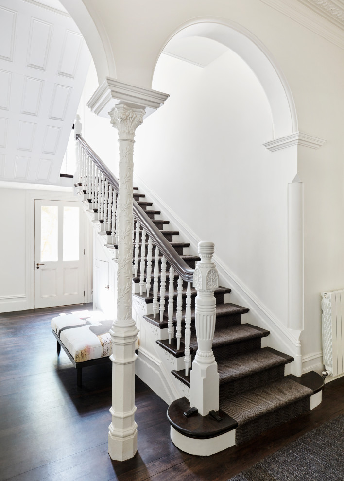 На фото: большая п-образная деревянная лестница в викторианском стиле с деревянными ступенями, деревянными перилами и панелями на стенах