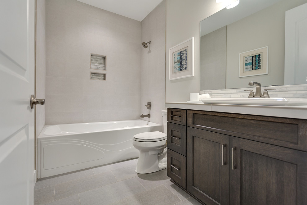 Photo of a large transitional master bathroom in Portland with recessed-panel cabinets, dark wood cabinets, an alcove tub, a shower/bathtub combo, a two-piece toilet, gray tile, porcelain tile, grey walls, porcelain floors, an undermount sink and tile benchtops.