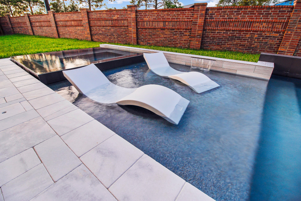 Example of a large minimalist backyard stone and custom-shaped pool design in Houston